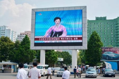 Norte-coreanos , em Pyongyang, caminham perto de uma tela gigante durante transmissão do anúncio do governo de que a Coreia do Norte realizou o seu quinto teste nuclear 9/09/ 2016. Crédito obrigatório para Kyodo/via REUTERS .