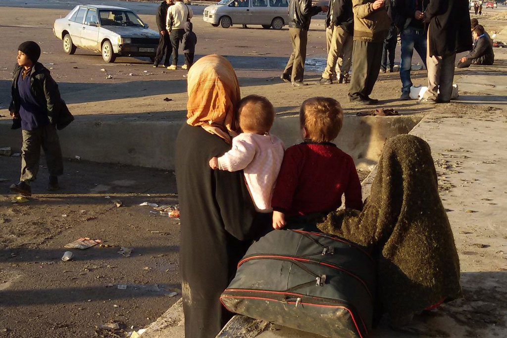 Uma mulher e seus filhos aguardam transporte em Alepo, na Síria / Foto: ONU - OCHA / L. Tom