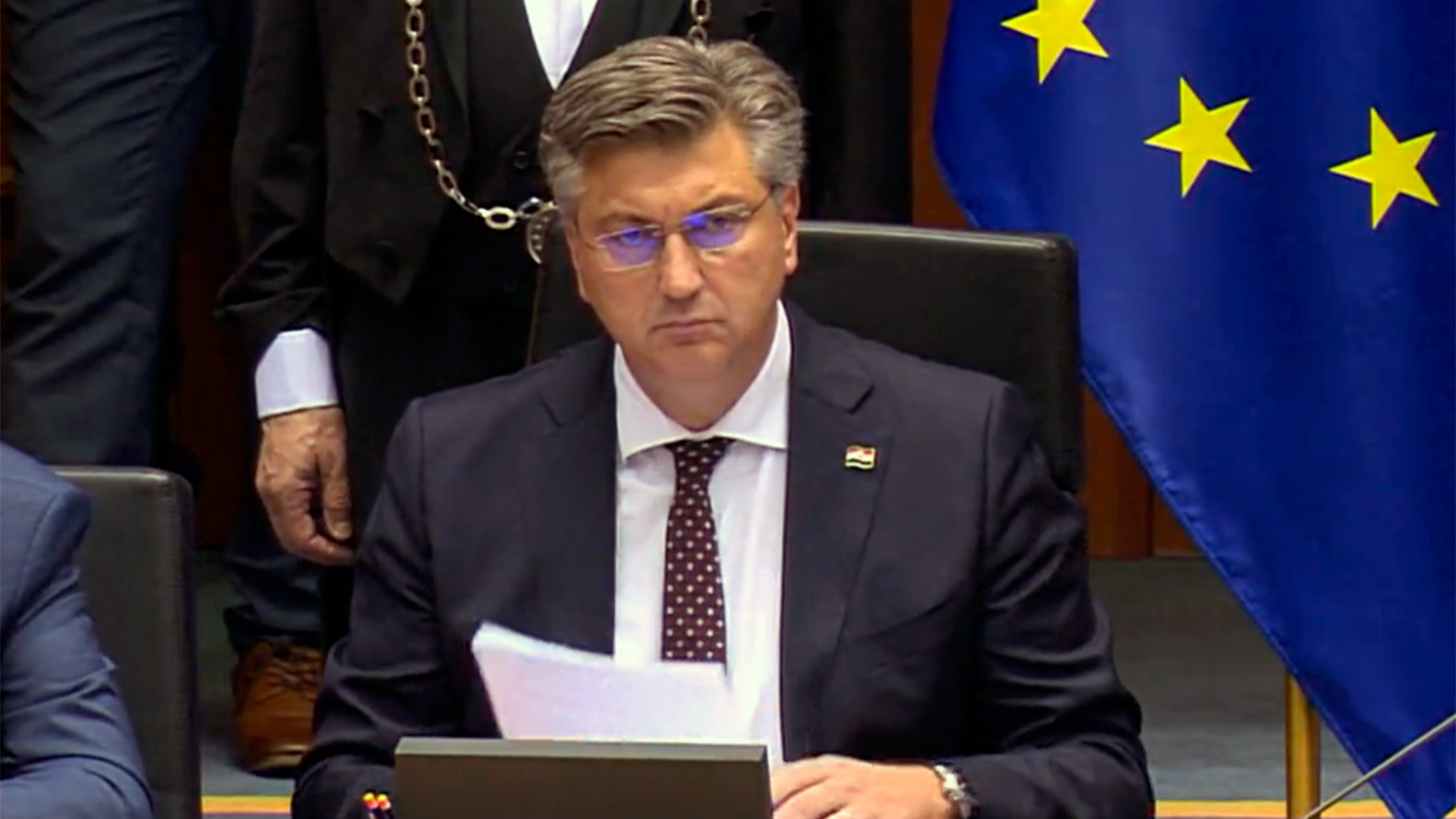 Ao centro, o primeiro-ministro da Croácia de óculos, terno, segura um papel