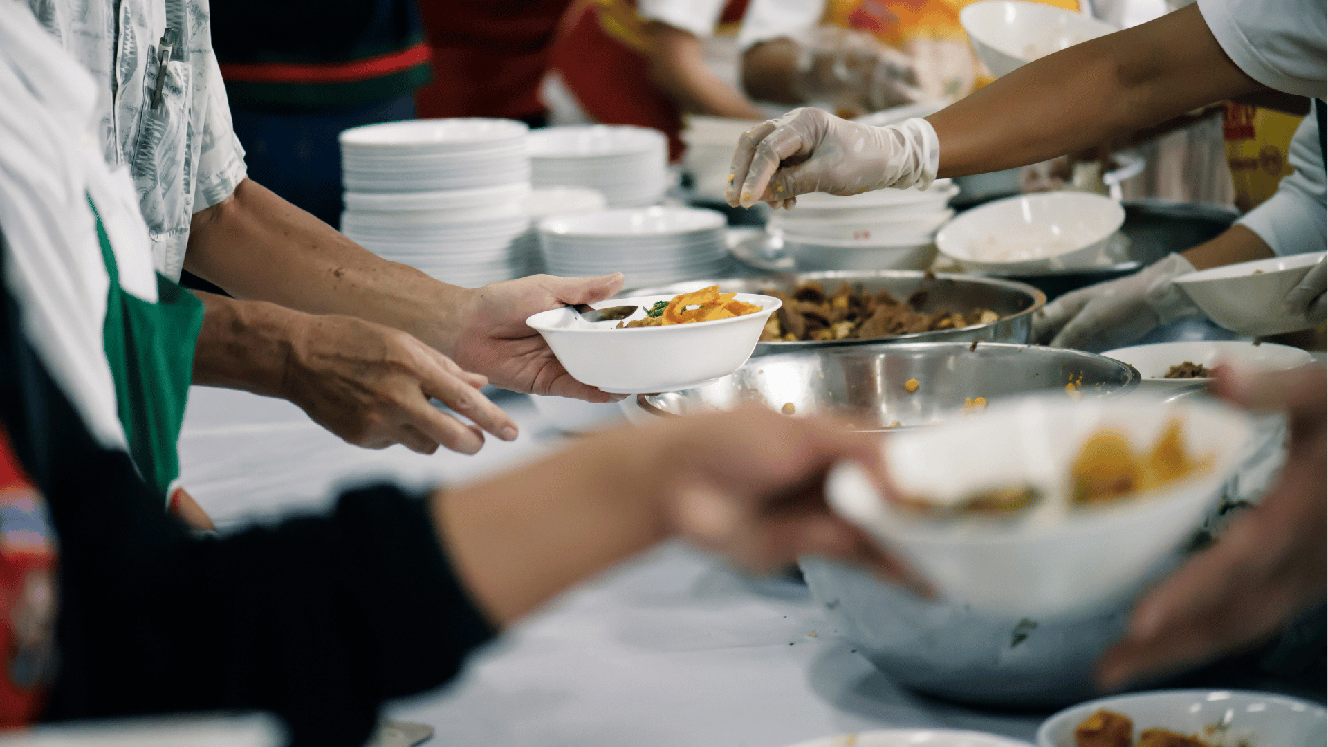 Voluntários servem refeições em gesto de solidariedade e caridade, oferecendo alimento a pessoas em situação de necessidade