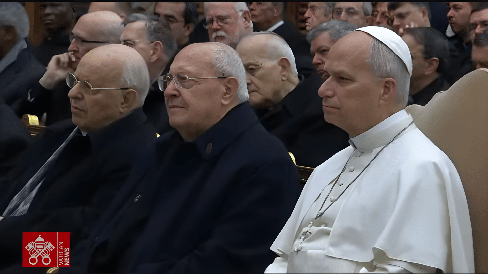 Papa Leão XIV e seus colaboradores da Cúria Romana O Papa Leão XIV, com suas habituais vestes brancas e cruz peitoral, aparece sentado ao lado de outros homens, membros da cúria romana