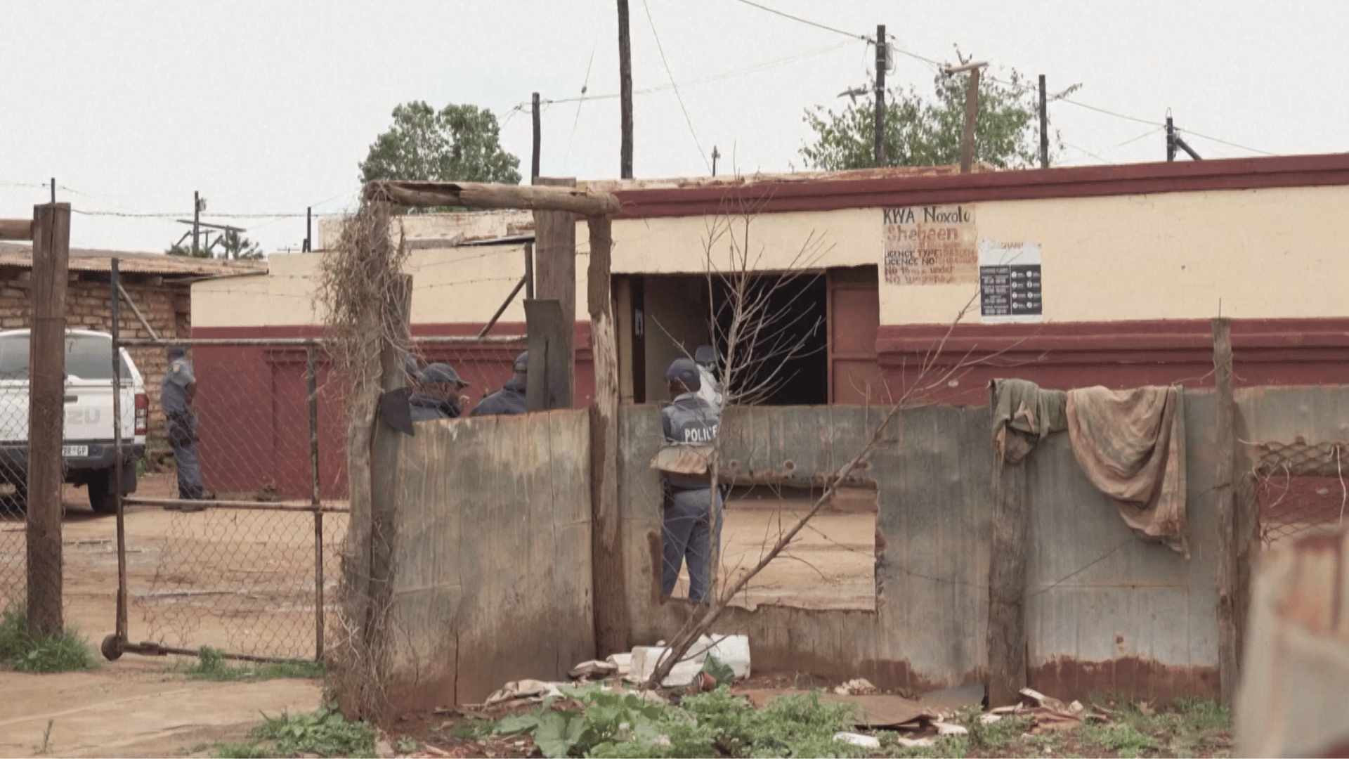 A imagem ilustra um bar em Bekkersdal, no subúrbio de Joanesburgo, alvo de ataque que deixou mortos e feridos. É possível ver alguns policiais no local.