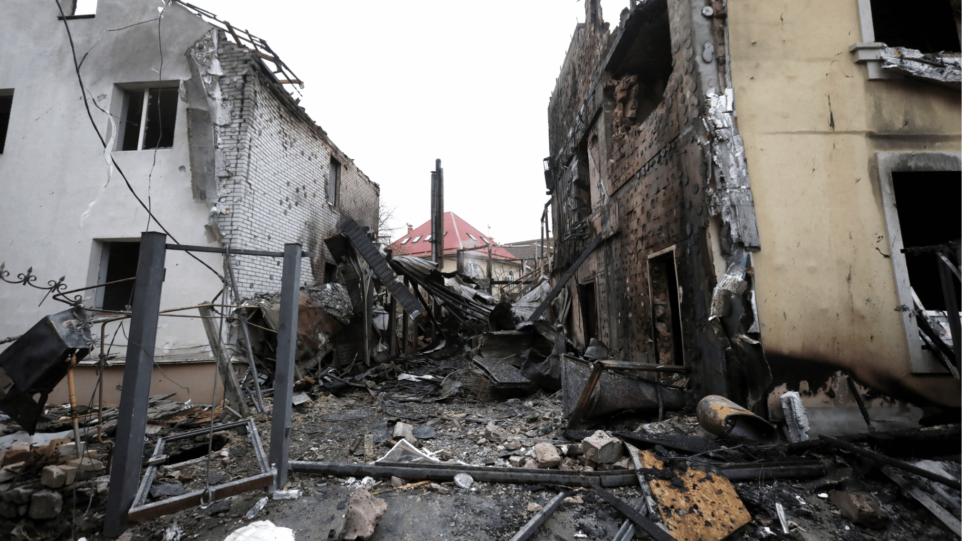 Prédios residenciais destruídos após ataque em um distrito de Kiev, com fachadas queimadas, escombros espalhados pelo chão e estruturas parcialmente colapsadas.