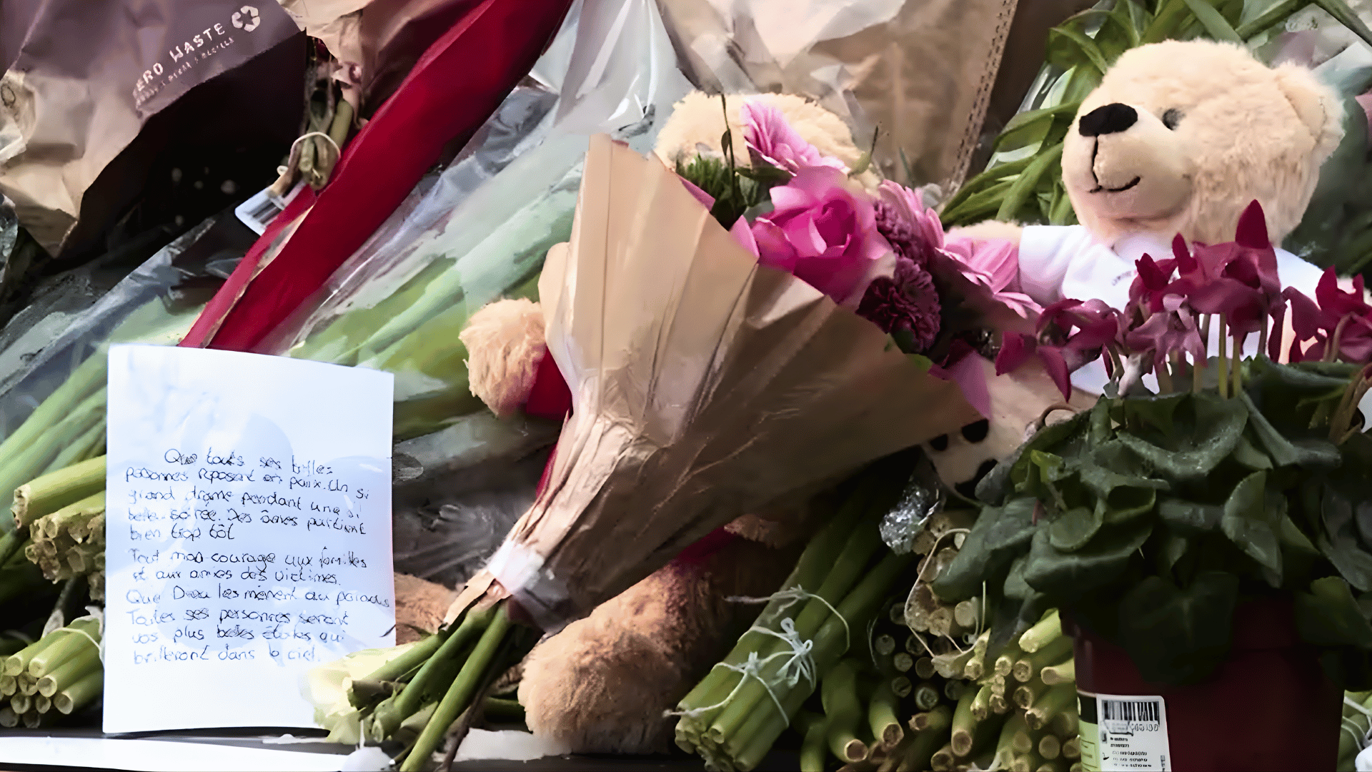 Flores, bilhetes e objetos de pelúcia são deixados em memorial improvisado em homenagem às vítimas de um incêndio, em espaço público.