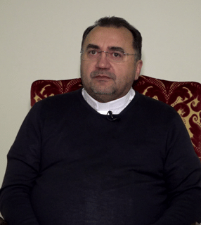 Padre Valdir sentado em poltrona estofada em entrevista para o Jornalismo da TV Canção Nova