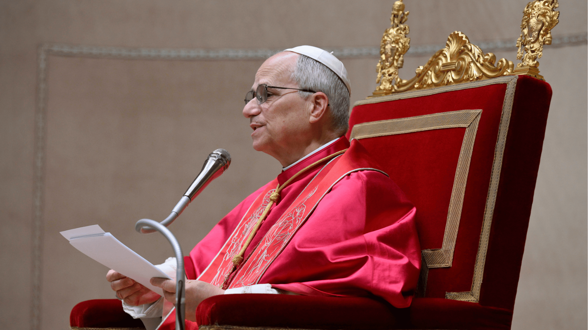 Papa Leão XIV discursa sentado em cadeira pontifícia durante audiência com o Corpo Diplomático, segurando o texto e falando ao microfone, no Vaticano.