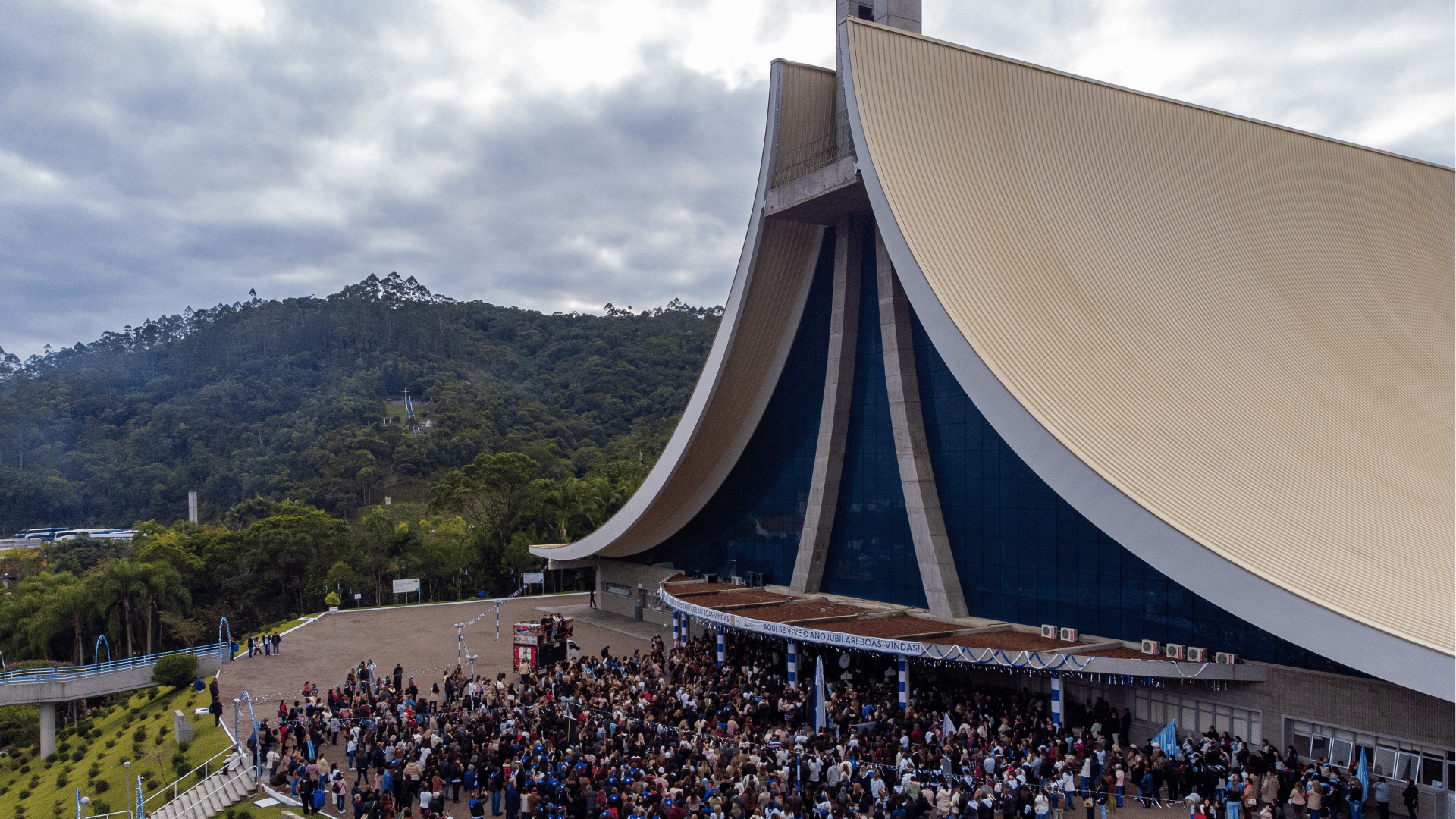 Fiéis reunidos em frente ao Santuário Santa Paulina, em Nova Trento (SC), durante celebração religiosa, com destaque para a arquitetura moderna do templo e a área externa lotada.