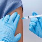 A foto mostra o braço de uma pessoa sendo vacinado