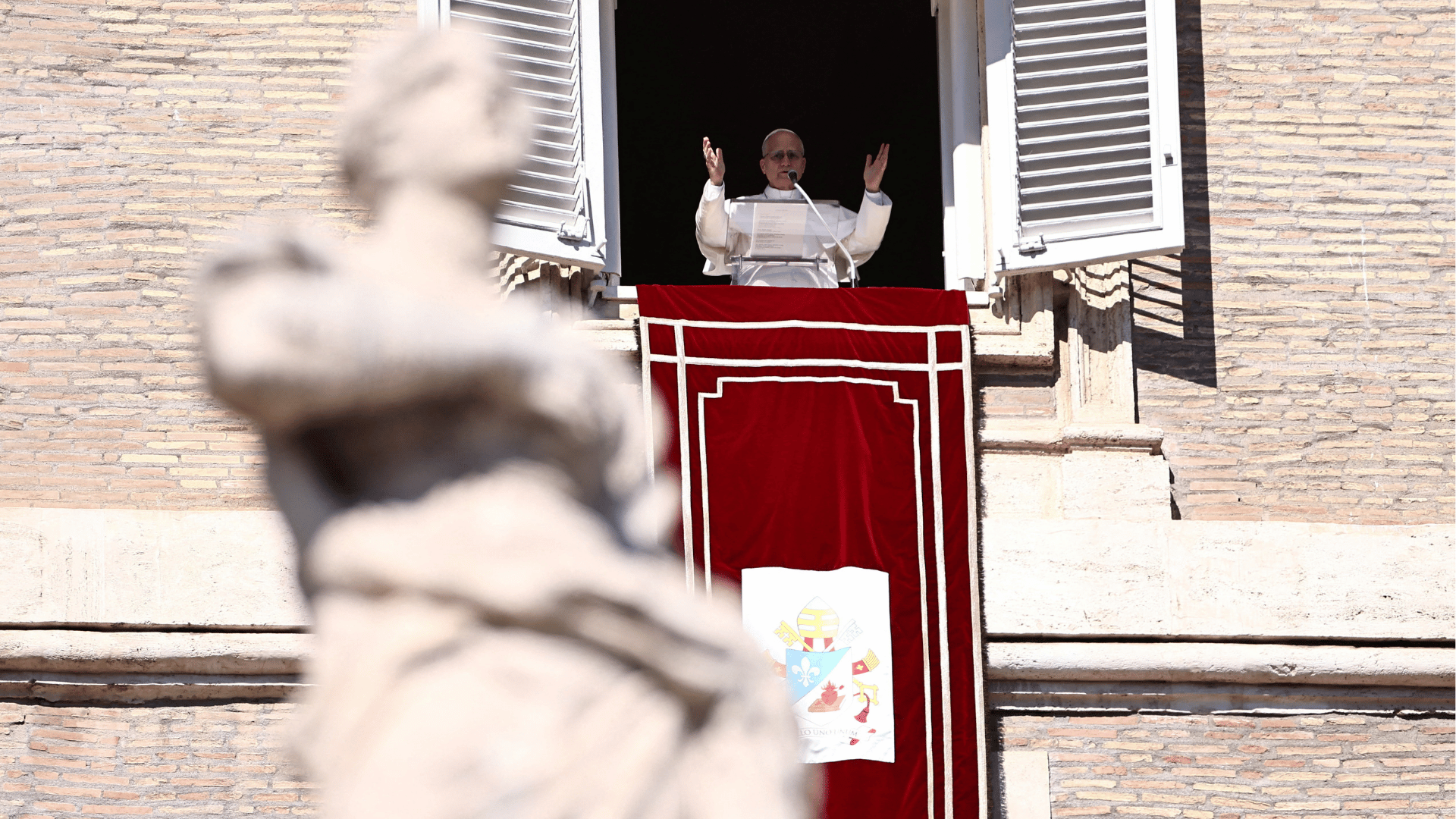 O Papa Leão XIV aparece acenando aos fiéis, de braços abertos, da janela do palácio apostólico