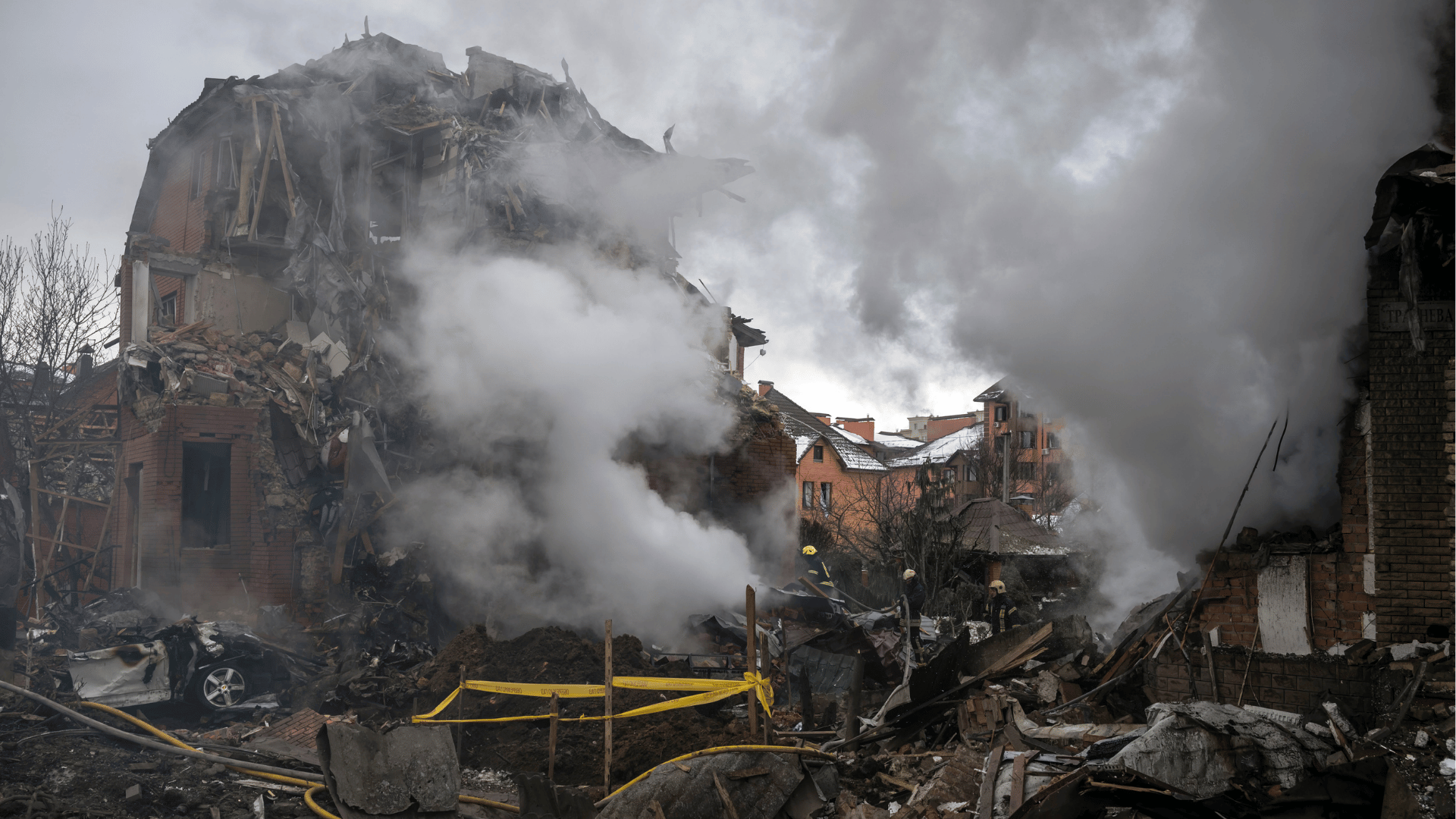 A imagem mostra o que parece ser um prédio destruído, com muita fumaça e destroços ao redor, após ataque com drones e mísseis