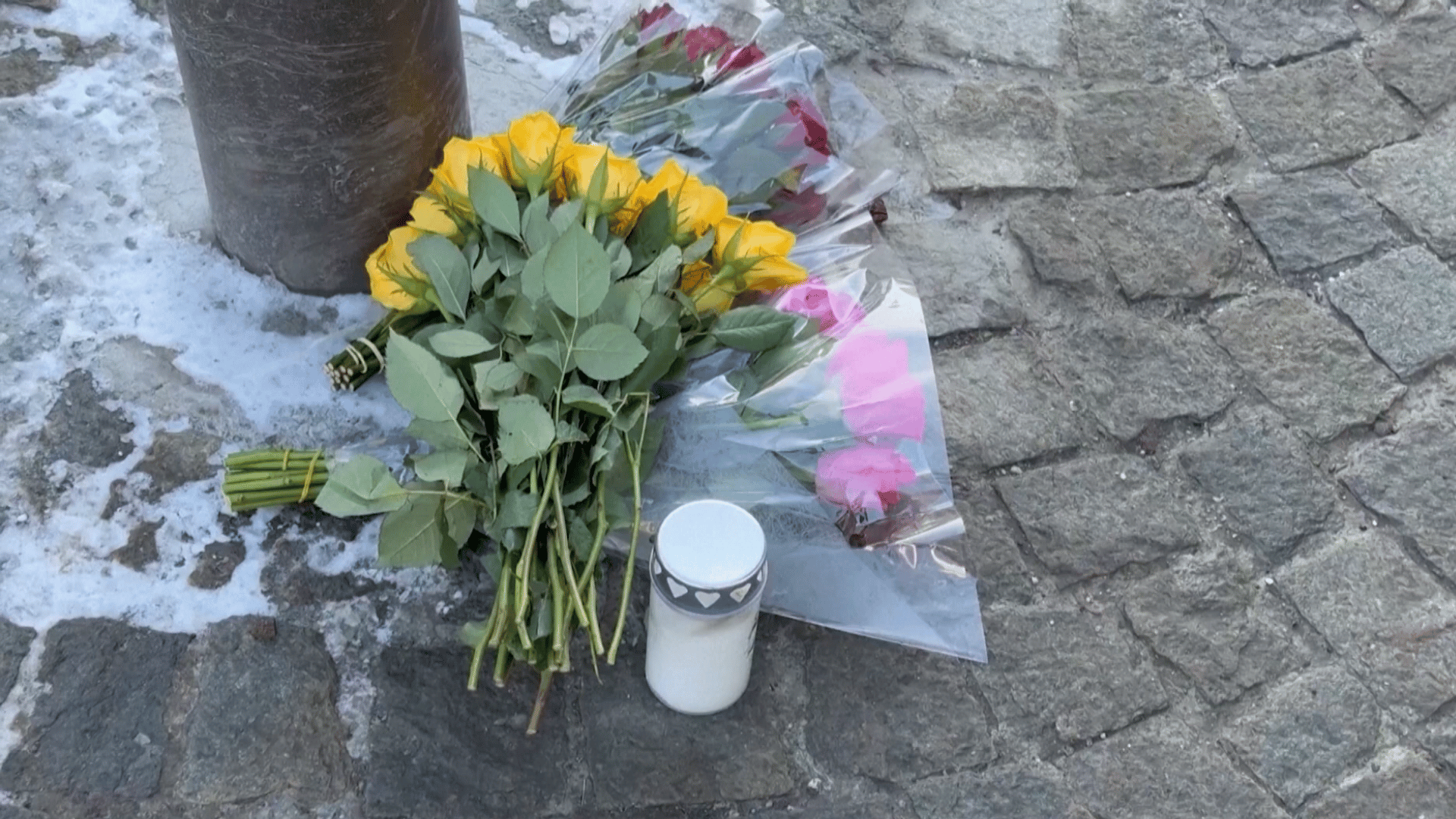 A imagem ilustra algumas flores depositadas no chão de pedra em memória das vítimas de um incêndio.