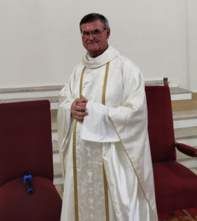 Padre Carlos José Feeburg A imagem ilustra um padre católicos vestindo uma casula branca.