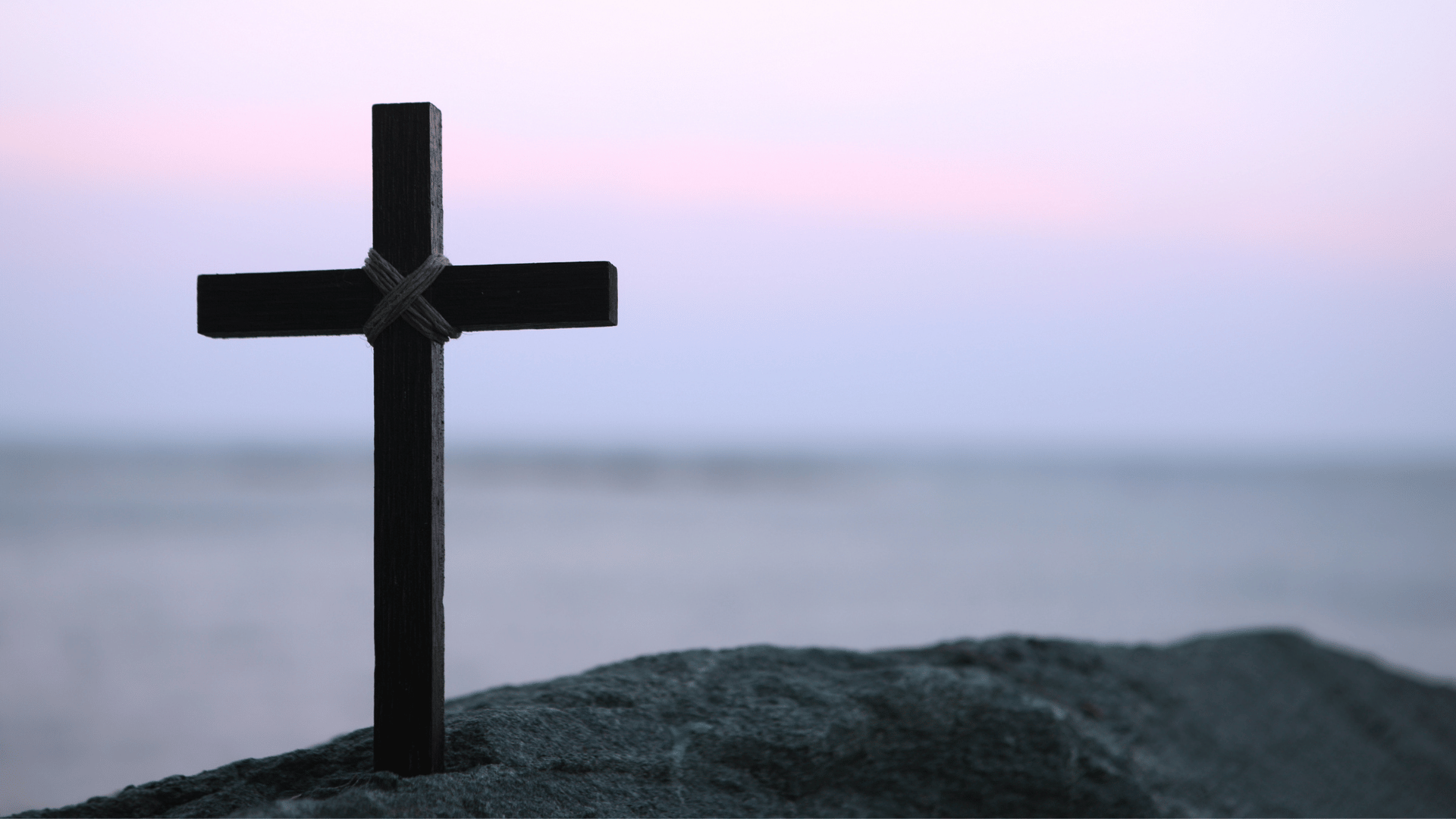 A imagem ilustra uma cruz de madeira fincada sobre a terra.