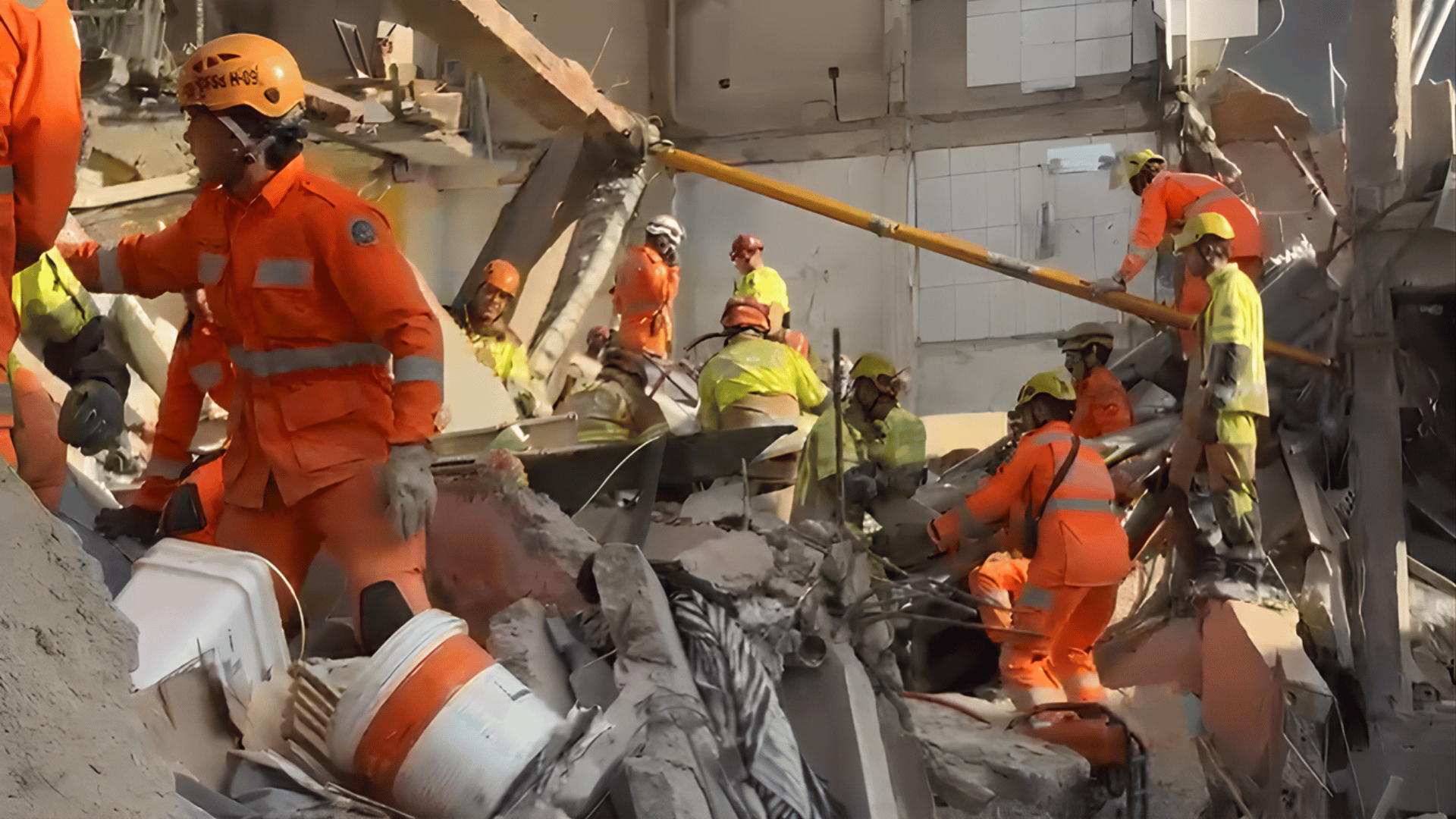 Equipes de resgate do Corpo de Bombeiros trabalham entre os escombros após desabamento de prédio em Belo Horizonte, utilizando capacetes e equipamentos de proteção.
