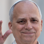 Papa Leão XIV sorrindo e acenando com a mão, vestindo batina branca e solidéu.