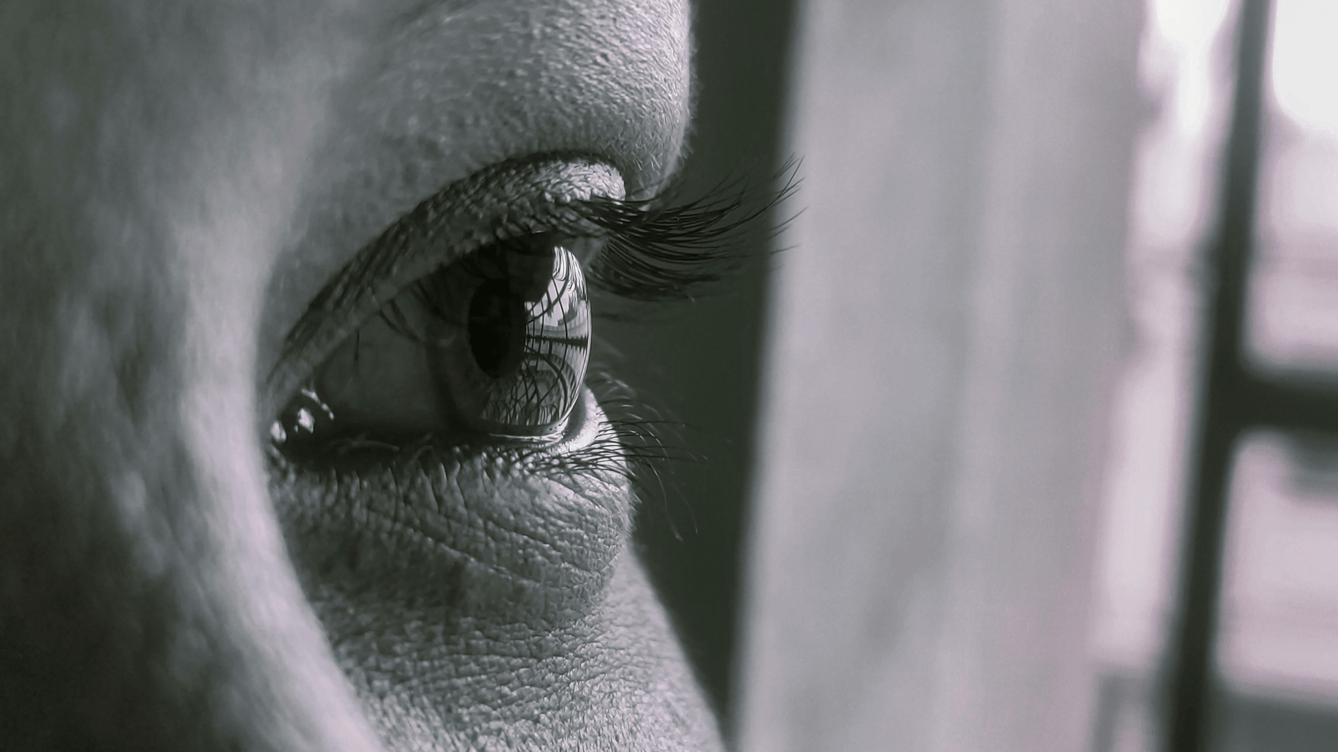 A imagem ilustra um olho humano, em plano fechado e tons monocromáticos.