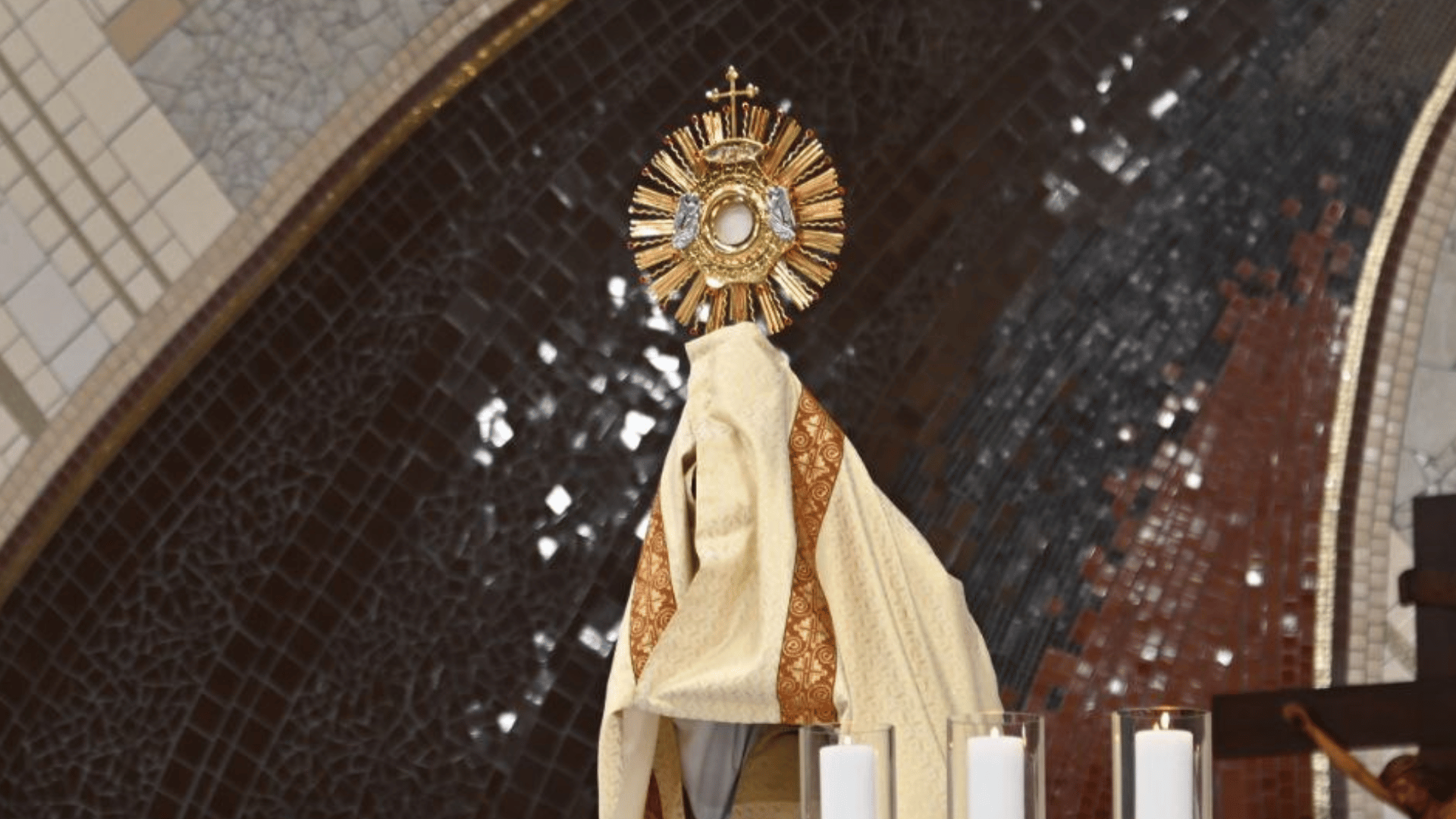 A imagem ilustra um padre segurando um ostensório com o Santíssimo Sacramento, elevando-o acima de si próprio em um gesto para abençoar os fiéis.