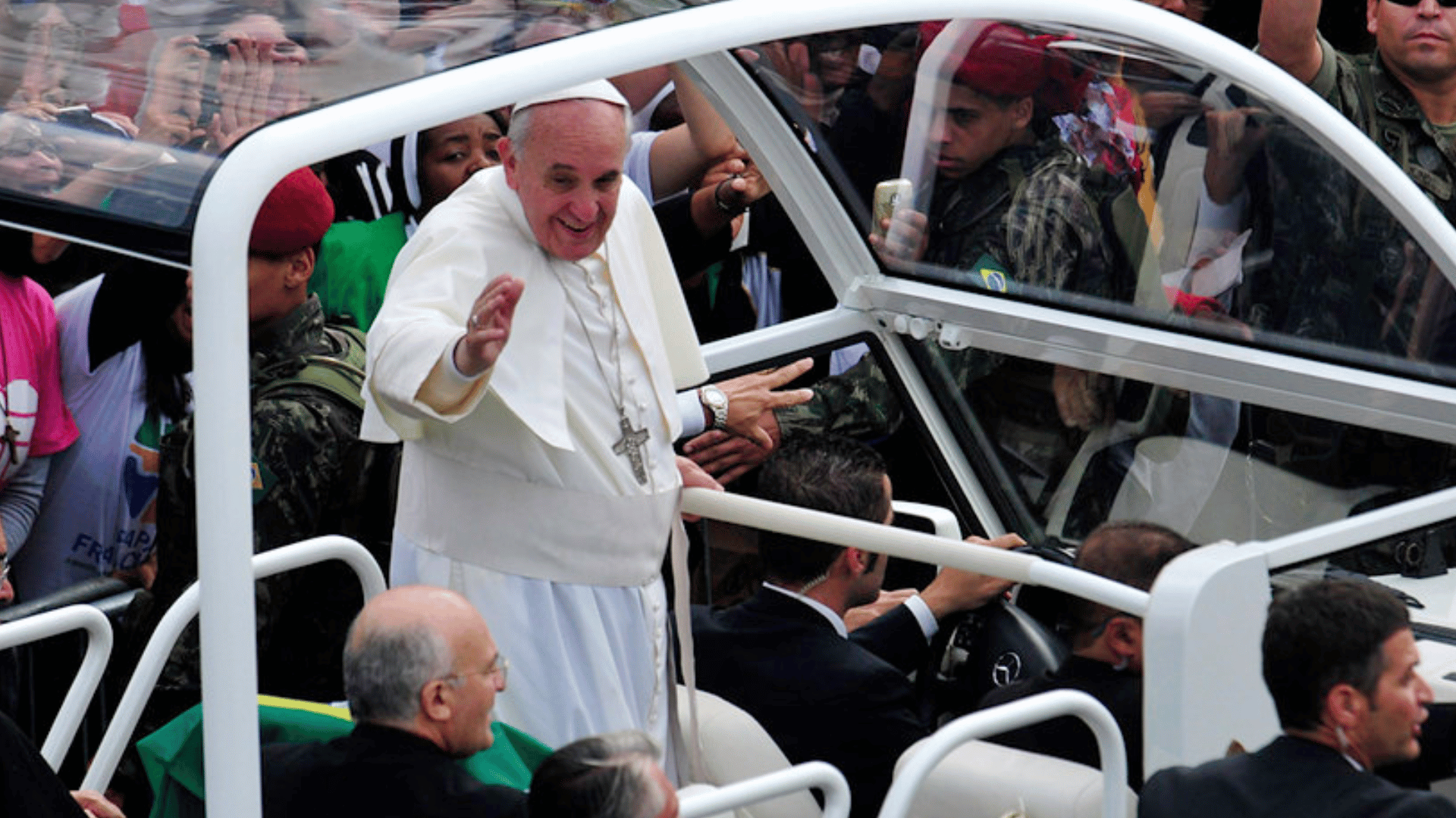 A imagem ilustra o Papa Francisco acenando do papamóvel para os fiéis na JMJ Rio 2013.