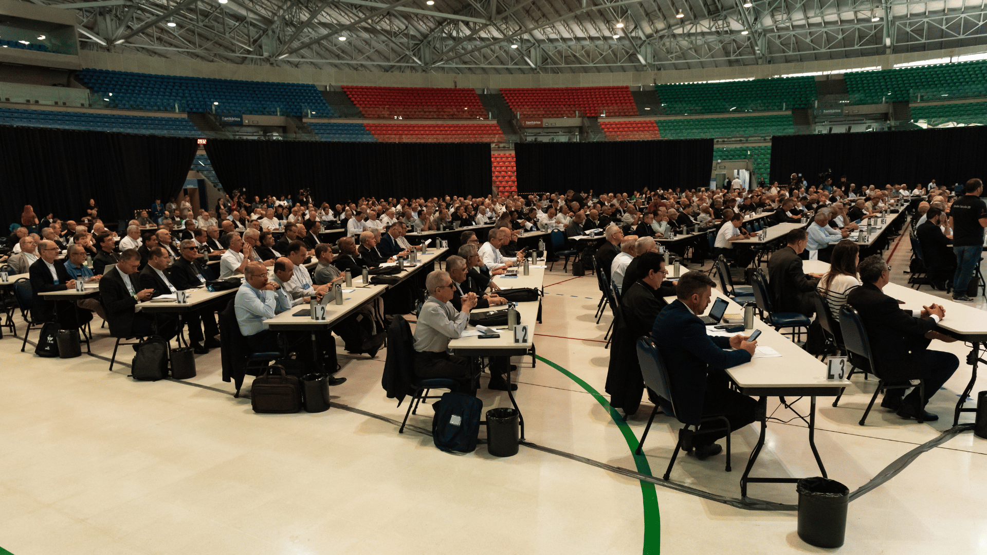 Bispos brasileiros sentados em mesas espalhadas pelo Centro de Eventos Padre Vítor Coelho de Almeida, em Aparecida, em 2024
