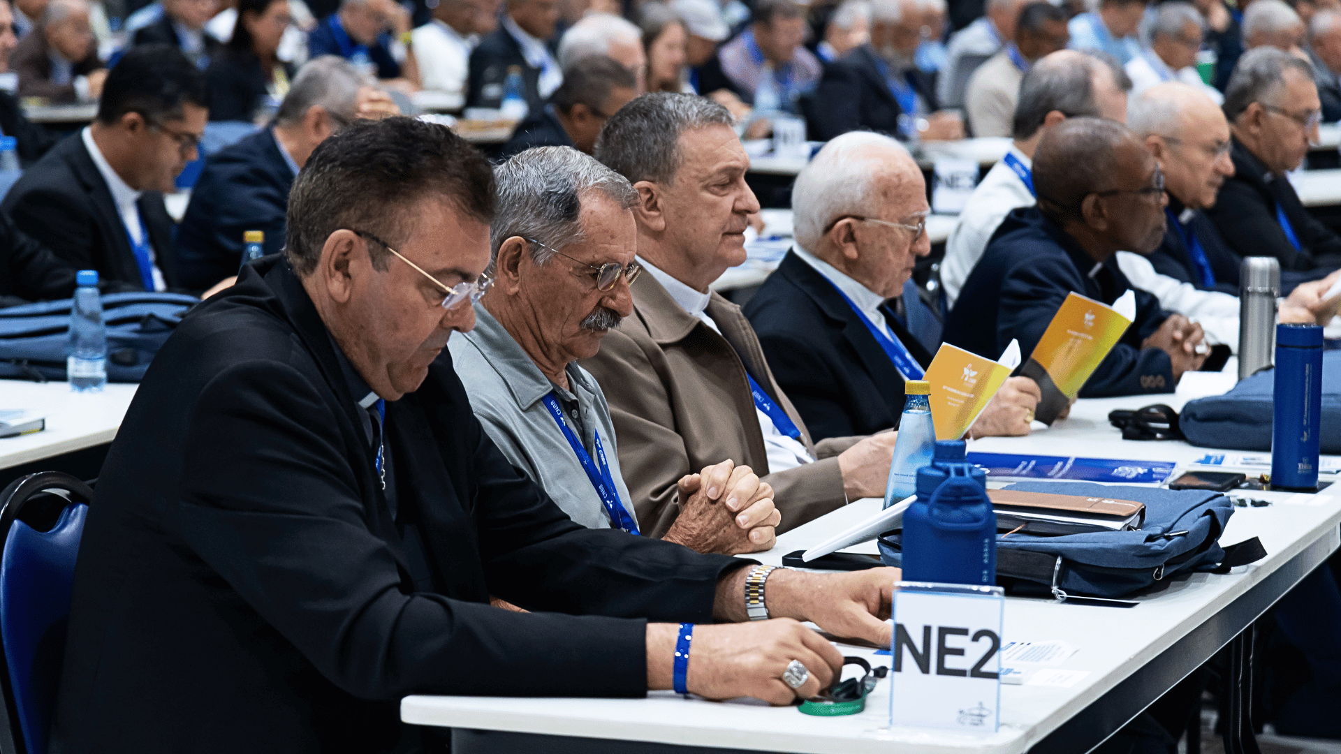 Bispos sentados em mesas durante sessões da Assembleia Geral da CNBB em Aparecida (SP).