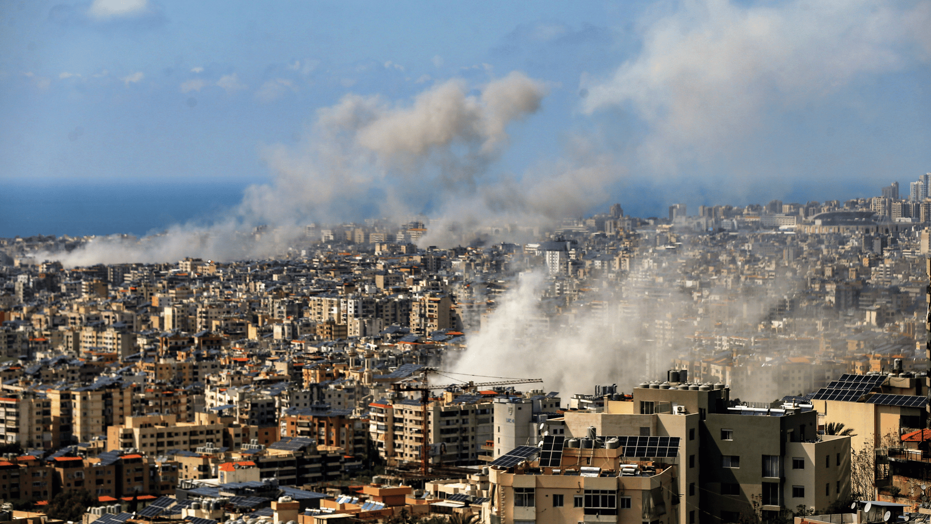 A imagem ilustra a cidade de Beirute com alguns focos de fumaça causados por ataques.