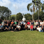 Missionários reunidos durante a Assembleia Geral da Canção Nova, em área externa com gramado e árvores, diante da imagem de Dom Bosco