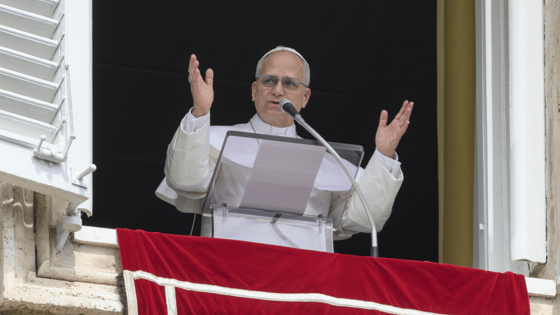 Papa Leão XIV renova apelo pela paz após rezar o Regina Caeli A imagem ilustra o Papa Leão XIV com suas habituais vestes pontifícias, semblantes sérios e braços erguidos enquanto fala diante de um microfone