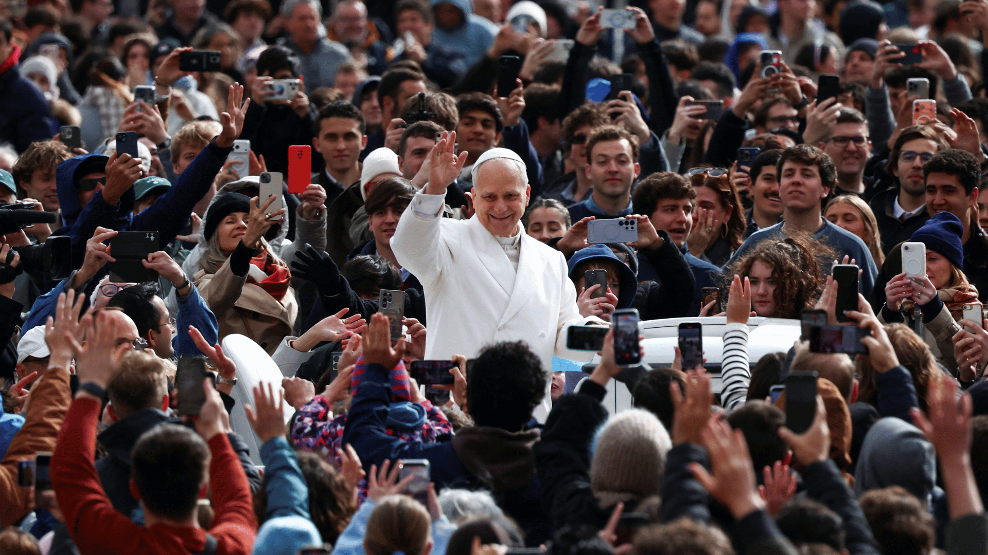 A imagem ilustra o Papa Leão XIV com o braço direito erguido, acenando para os fiéis reunidos na Praça São Pedro.