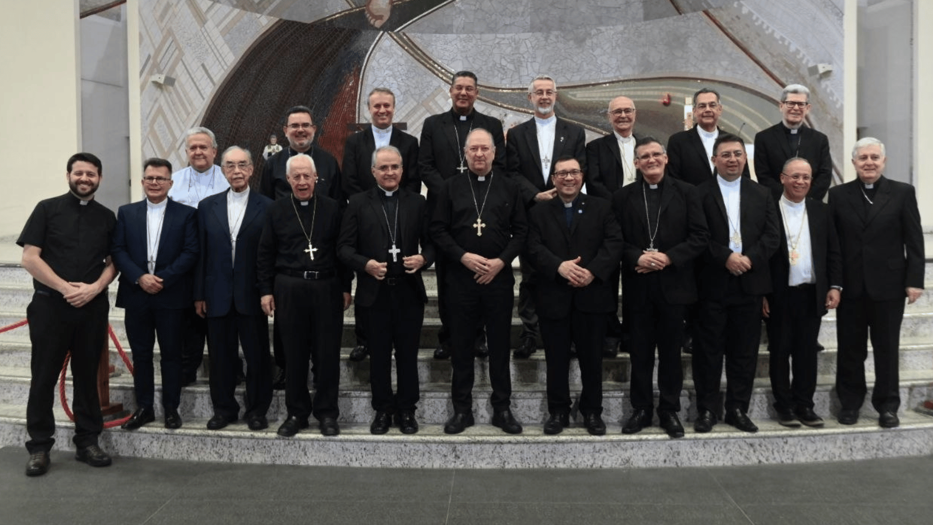A imagem ilustra um grupo de bispos e padres posando para uma fotografia, divididos em duas fileiras.