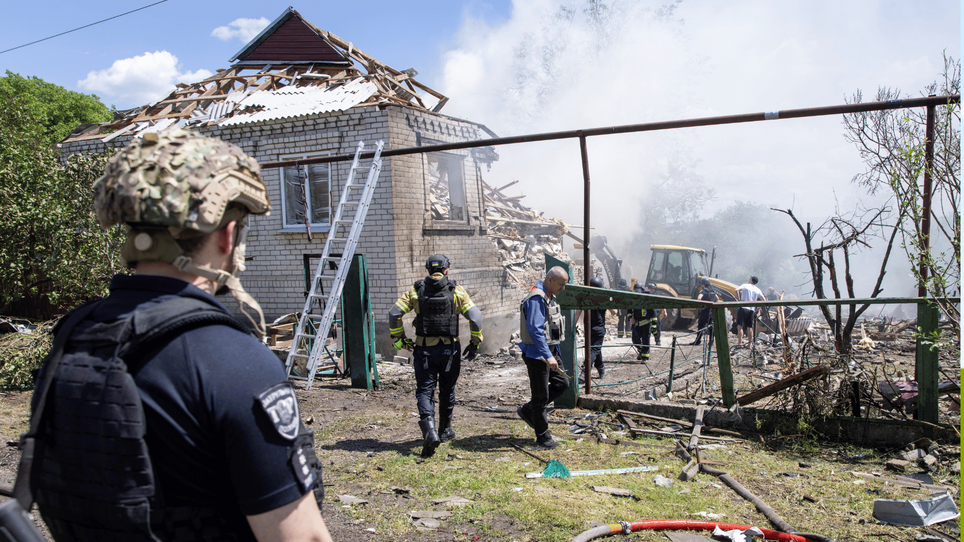 A imagem mostra uma casa destruída e homens que trabalham ao redor