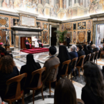 Papa Leão XIV discursa durante encontro com representantes cristãos e muçulmanos em salão do Vaticano, diante de religiosos e convidados sentados.