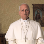 Papa grava uma mensagem em vídeo em ambiente interno. Ao fundo, aparecem uma imagem religiosa emoldurada e uma escultura de Nossa Senhora.