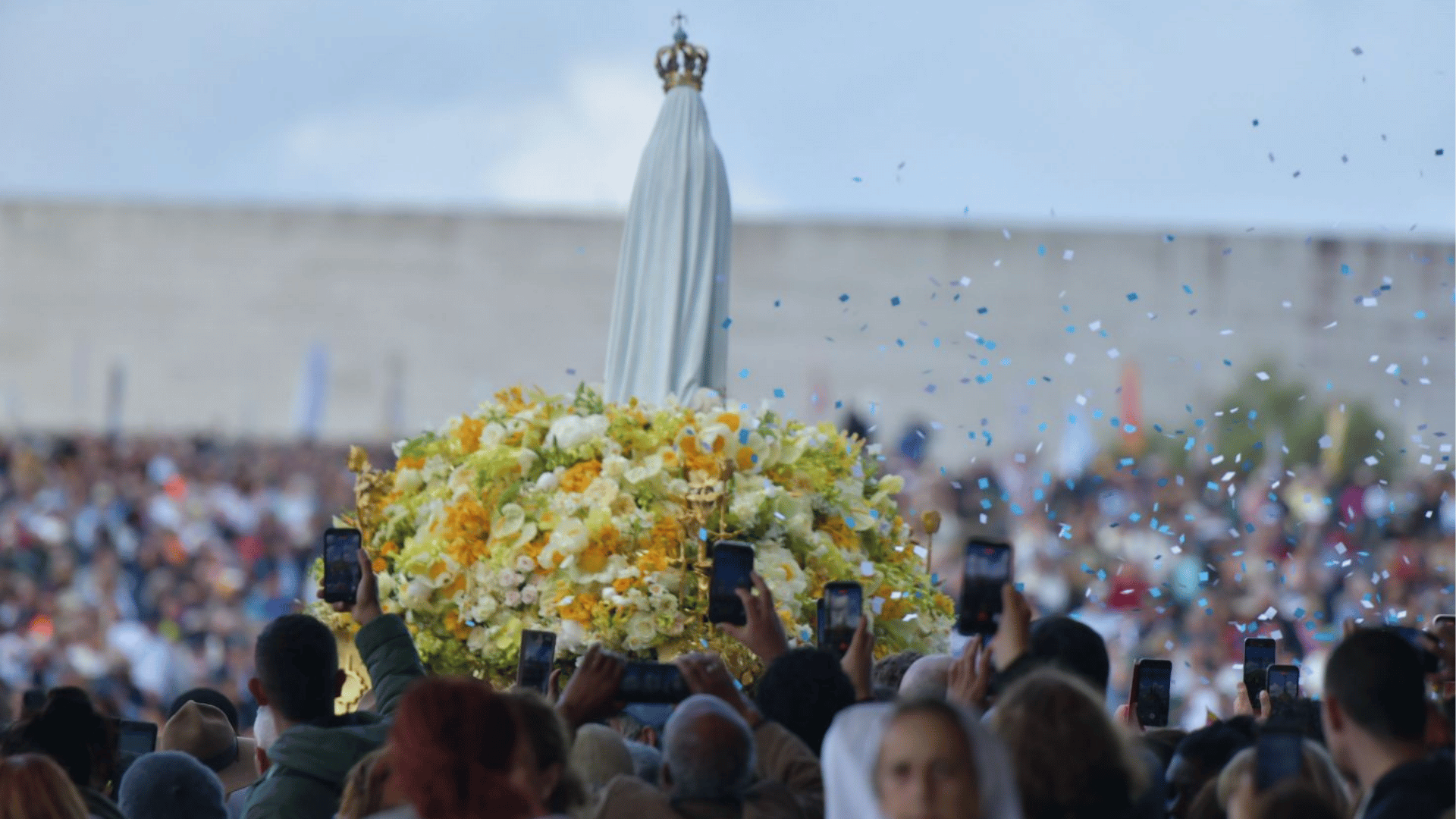 A imagem mostra a imagem de Nossa Senhora de Fátima em cima do andor, de costas, e a multidão ao redor