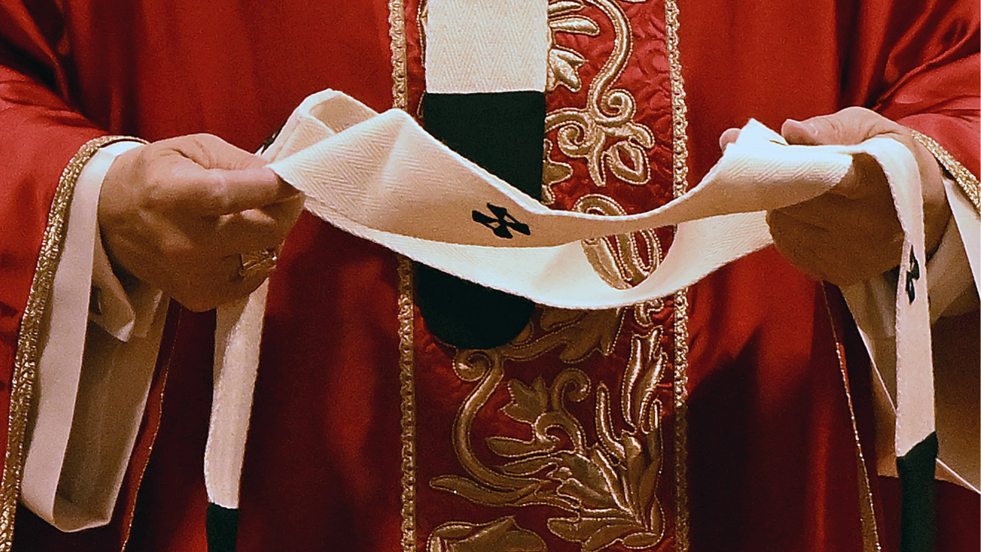 Detalhe da cerimônia de entrega do pálio: Papa veste paramento litúrgico vermelho e segura o pálio branco, faixa de lã ornamentada com cruzes pretas, símbolo da comunhão dos arcebispos metropolitanos com o Sucessor de Pedro.