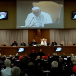 Papa Leão XIV na sessão de encerramento do Consistório extraordinário no Vaticano, sentado à mesa principal diante dos cardeais reunidos na Sala do Sínodo. Ao fundo, um telão exibe a imagem do Pontífice durante seu discurso.