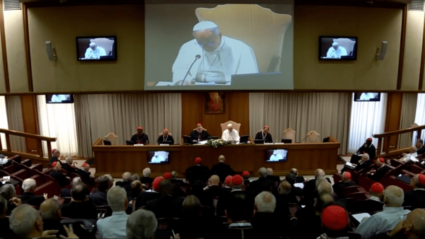 Papa Leão XIV na sessão de encerramento do Consistório extraordinário no Vaticano, sentado à mesa principal diante dos cardeais reunidos na Sala do Sínodo. Ao fundo, um telão exibe a imagem do Pontífice durante seu discurso.