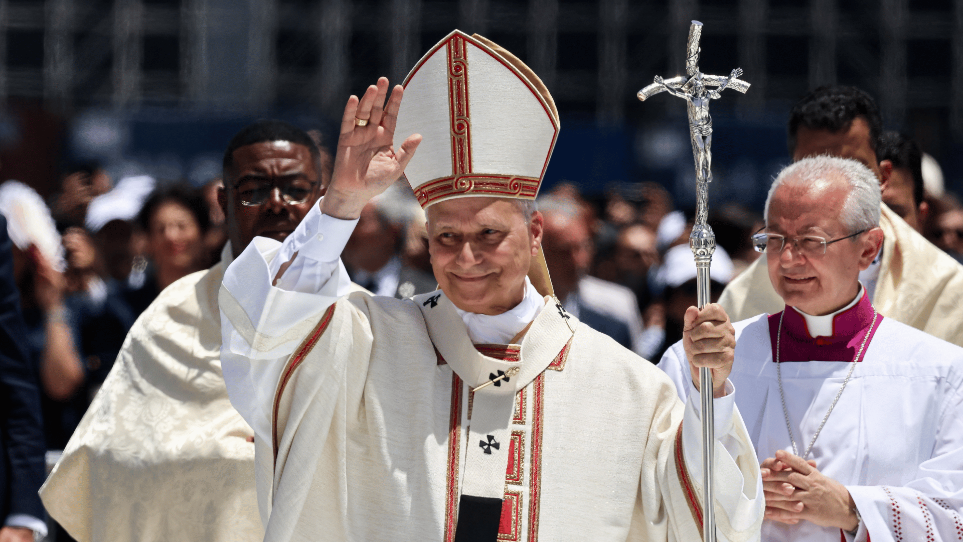 Papa Leão XIV saúda fiéis presentes na Missa em Tenerife A imagem ilustra o Papa Leão XIV paramentado com vestes litúrgicas e a férula papal em sua mão esquerda. Com a mão direita, ele acena para o povo.