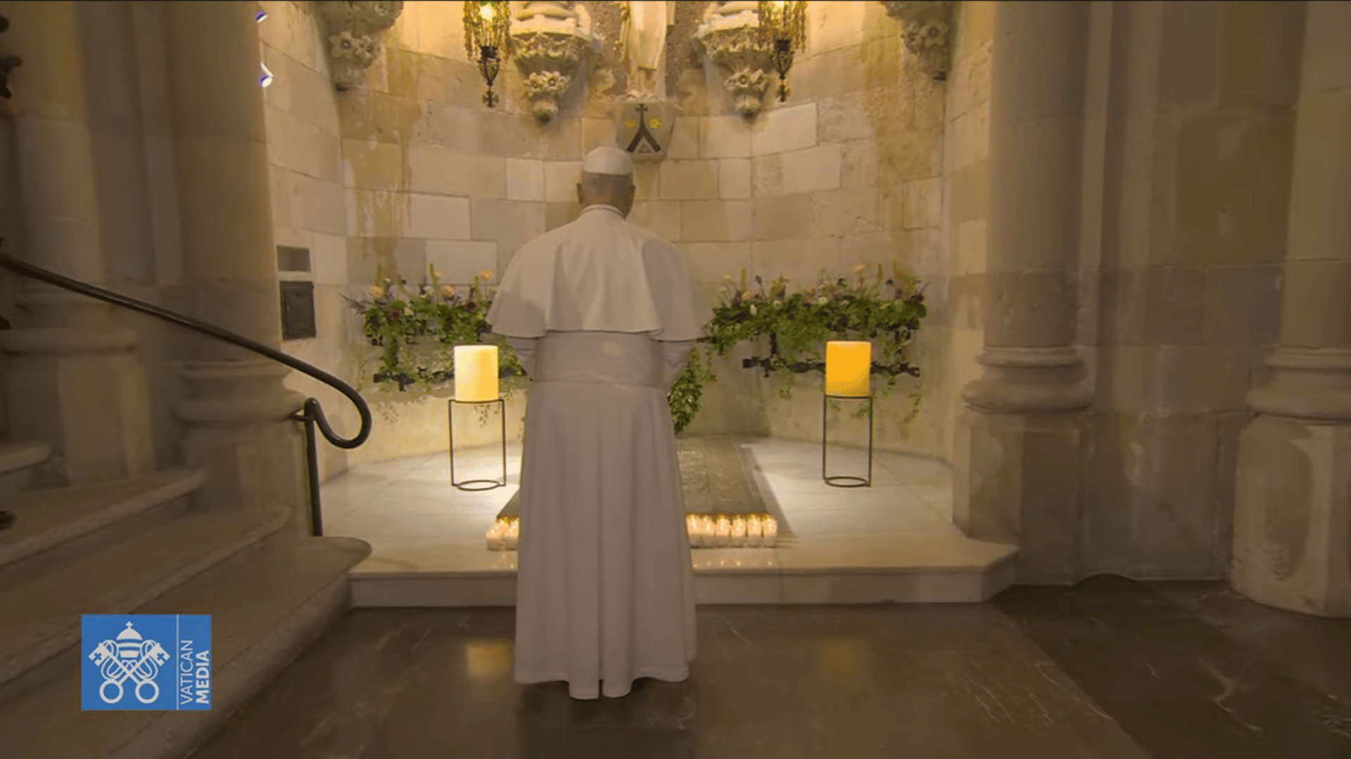 O Papa Leão XIV aparece com suas habituais vestes brancas em pé diante do túmulo de Antoni Gaudí . Há flores e velas no local.