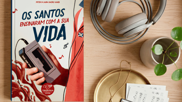 Livro Os Santos Ensinaram com a sua Vida, da Editora Canção Nova, sobre uma mesa ao lado de um toca-fitas portátil, fones de ouvido, uma planta e outros objetos decorativos.