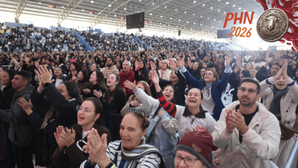 Fiéis participam da pregação do Padre Ailton no PHN 2026, com braços erguidos e aplausos no Centro de Evangelização.