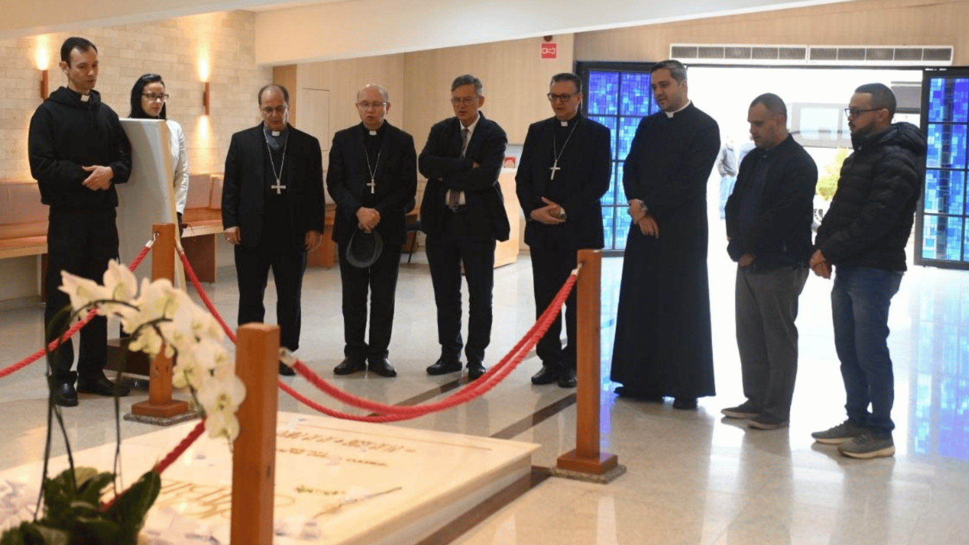 A foto mostra um grupo composto pelo jornalista Paolo Ruffini, e comitiva ao redor do túmulo do padre Jonas Abib