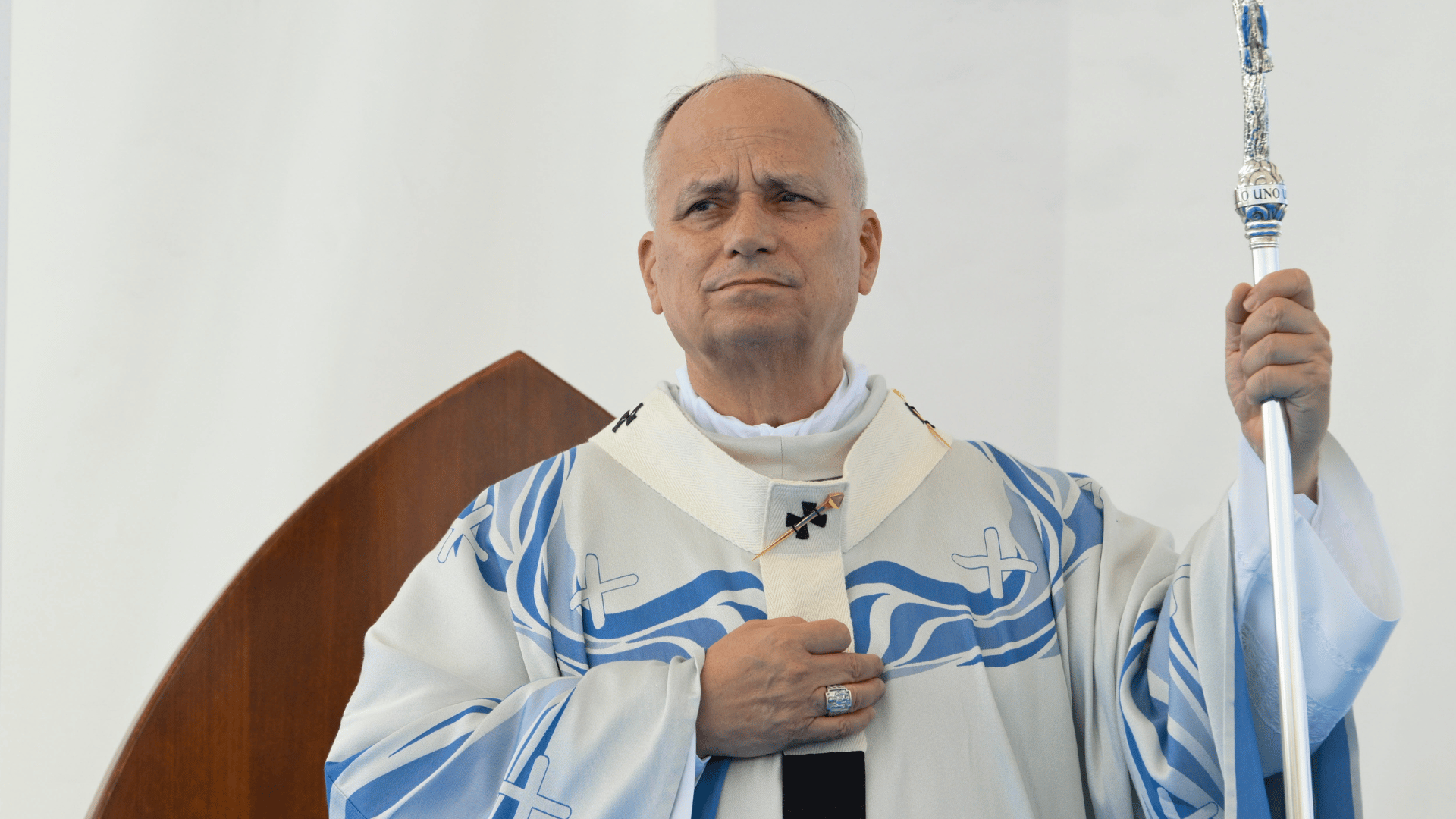 Papa Leão XIV durante Missa em Lampedusa A imagem ilustra o Papa Leão XIV, com expressão séria, vestida com paramentos litúrgicos brancos com detalhes azuis, durante a celebração da Missa