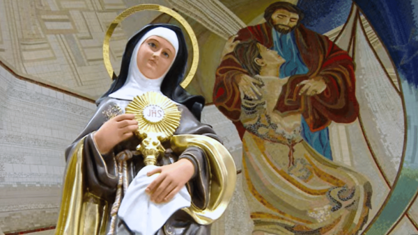 Imagem de Santa Clara de Assis, tendo como imagem de fundo o painel do Santuário do Pai das Misericórdias.