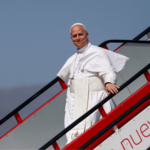 Papa Leão XIV desce a escada da aeronave ao chegar para uma viagem apostólica, vestido de branco e sorrindo para os presentes.
