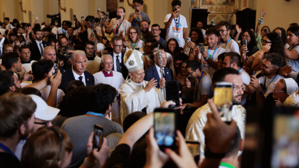 Papa Leão XIV percorre o corredor da basílica após a Missa, cercado por fiéis que registram o momento com celulares.