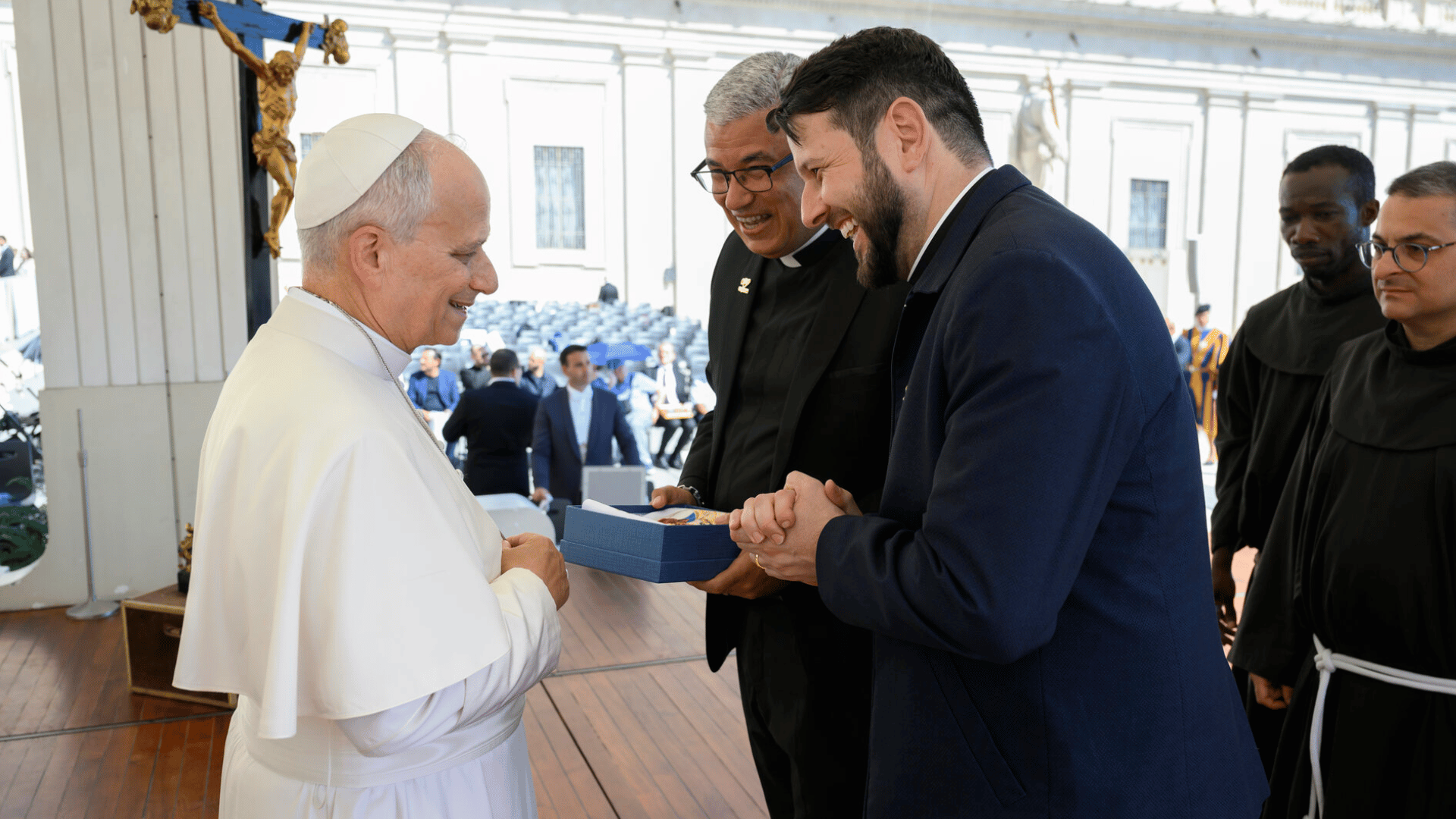 A imagem mostra o padre Roger Luis e o padre Donizete Heleno em pé, diante do Papa Leão XIV, que também está em pé.