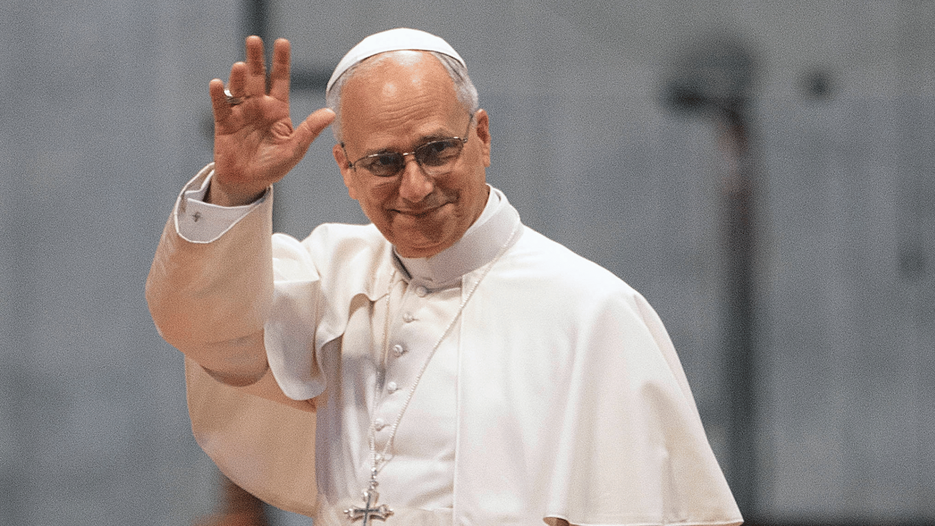 Papa Leão XIV A imagem ilustra o Papa Leão XIV, vestido com suas habituais vestes pontifícias brancas, com o braço direito erguido, acenando.