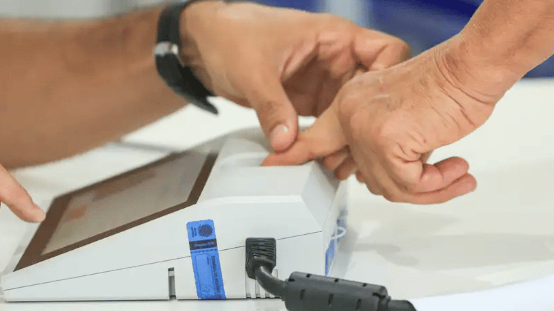 Eleitor posiciona o dedo no leitor biométrico durante o processo de votação em uma urna eletrônica.