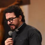 Padre Fábio de Melo aparece em um plano fechado de perfil, olhando para baixo com expressão serena enquanto segura um microfone. Tema: "Pela verdade sereis curados"