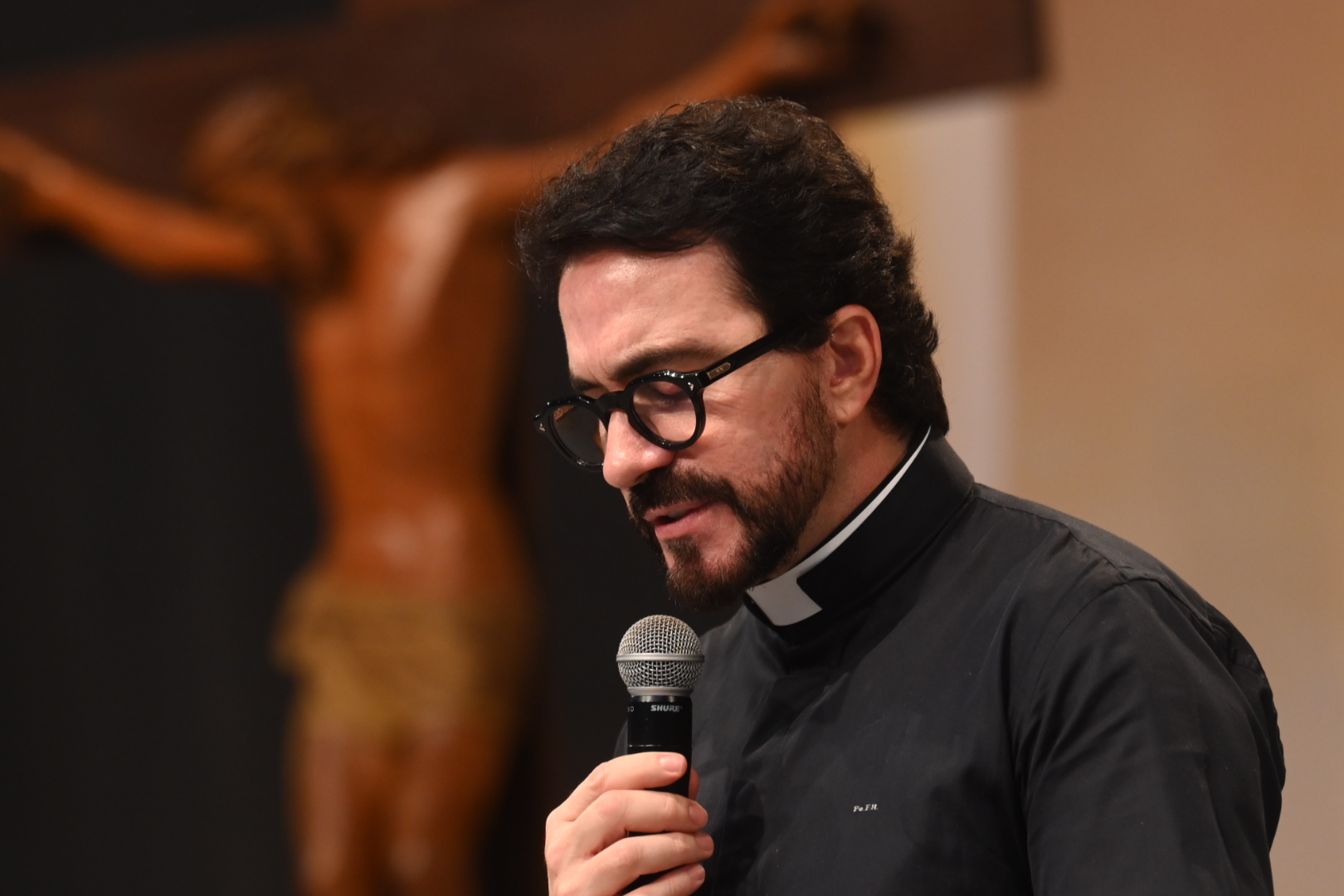 Padre Fábio de Melo aparece em um plano fechado de perfil, olhando para baixo com expressão serena enquanto segura um microfone. Tema: "Pela verdade sereis curados"